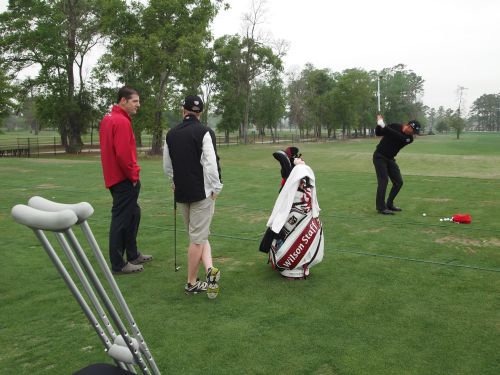 Padraig Harrington practices as caddy, Ronan Flood and Wilson Staff's Ron Graham and his crutches. look on
