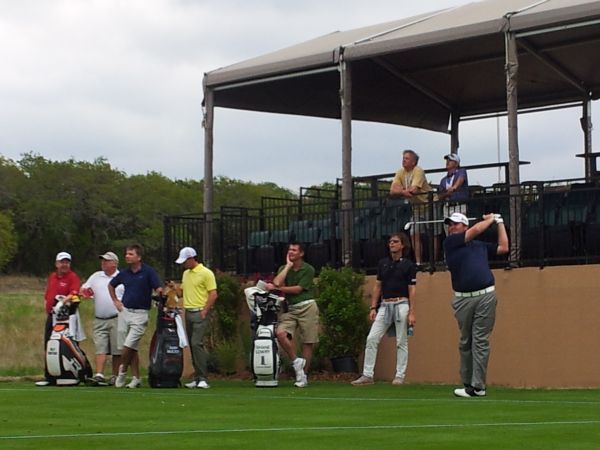 Shane Lowry tees off the par three 16th watched by coach, Neil Manchin (black shirt) and with Rory McIlroy on his mobile phone. (Photo - www.golfbytourmiss.com)