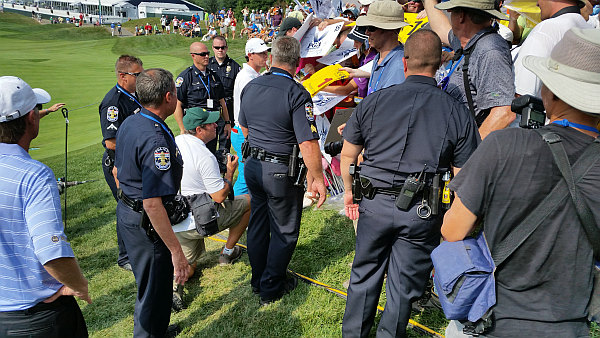 No fewer than seven uniform police officers providing a shield around World No. 1 Rory McIlroy as his signs autographs. (Photo - www.golfbytourmiss.com)