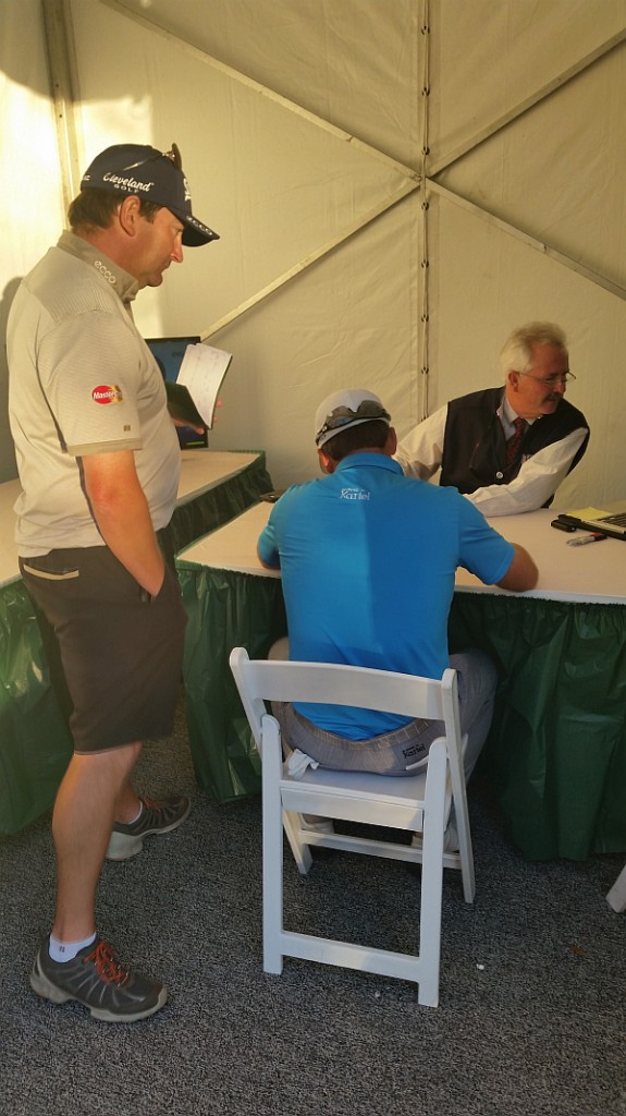 Caddy Ken Comboy watches over Graeme McDowell as he signs his card for the last time in 2014.  PGA Tour recorder 'Montana' and former caddy to  Billy Mayfair checks the figures.  (Photo - www.golfbytourmiss.com)