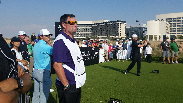 Stephen Gallacher tees off the 14th with his caddy Damien Moore in front and with Rory McIlroy and his caddy, Claudine Foong looking on.