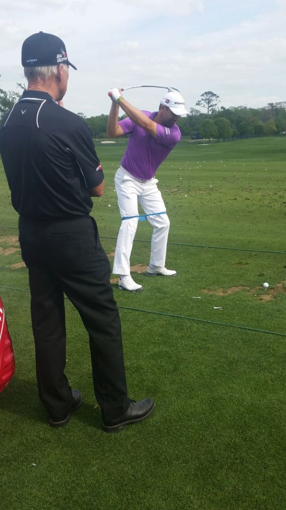 Padraig Harrington, and with a training aid wrapped around his legs, practices under the watchful eye of coach Pete Cowen.  (Photo - www.golfbytourmiss.com)