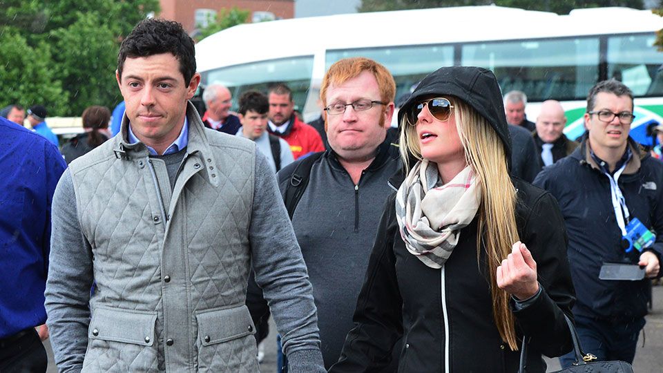Rory hand-in-hand with Erica Stoll and with his red-haired security official, sporting a not so happy face, caught in the middle of this Getty Images snap.