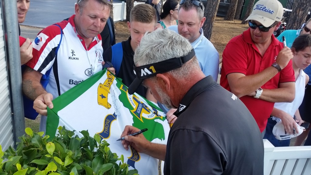 Darren Clarke signs his name under that of Rory McIlroy on a Northern Ireland county flag.