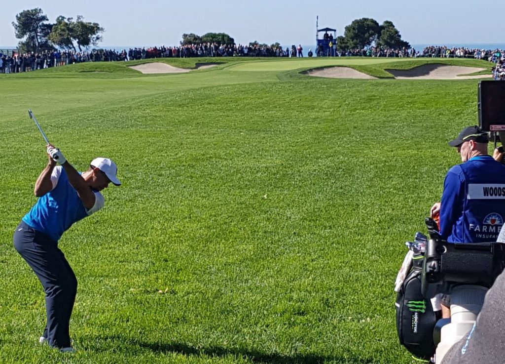 Tiger Woods plays his second shot from very damp rough down the first hole on day one of the Farmers Insurance Open.