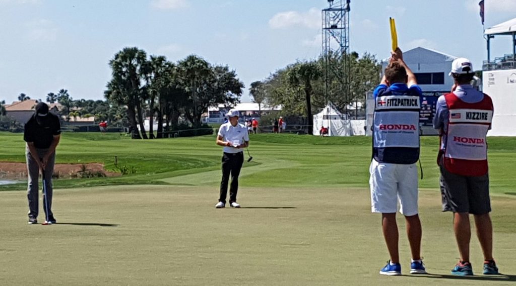 Matthew Fitzpatrick awaits to putt out for par as American Patton Kizzire holes out for birdie on the final green at PGA National.