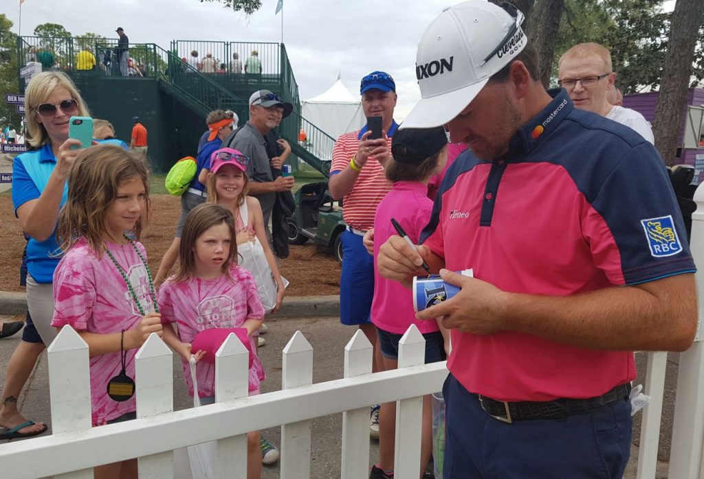 Graeme McDowell delights these two young fans signing a mug after his final round 67.