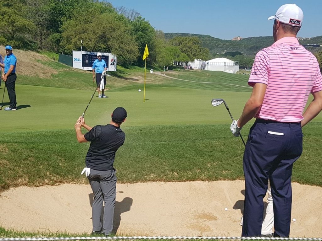 Justin Thomas watches McIlroy play a practice bunker shot at 16.