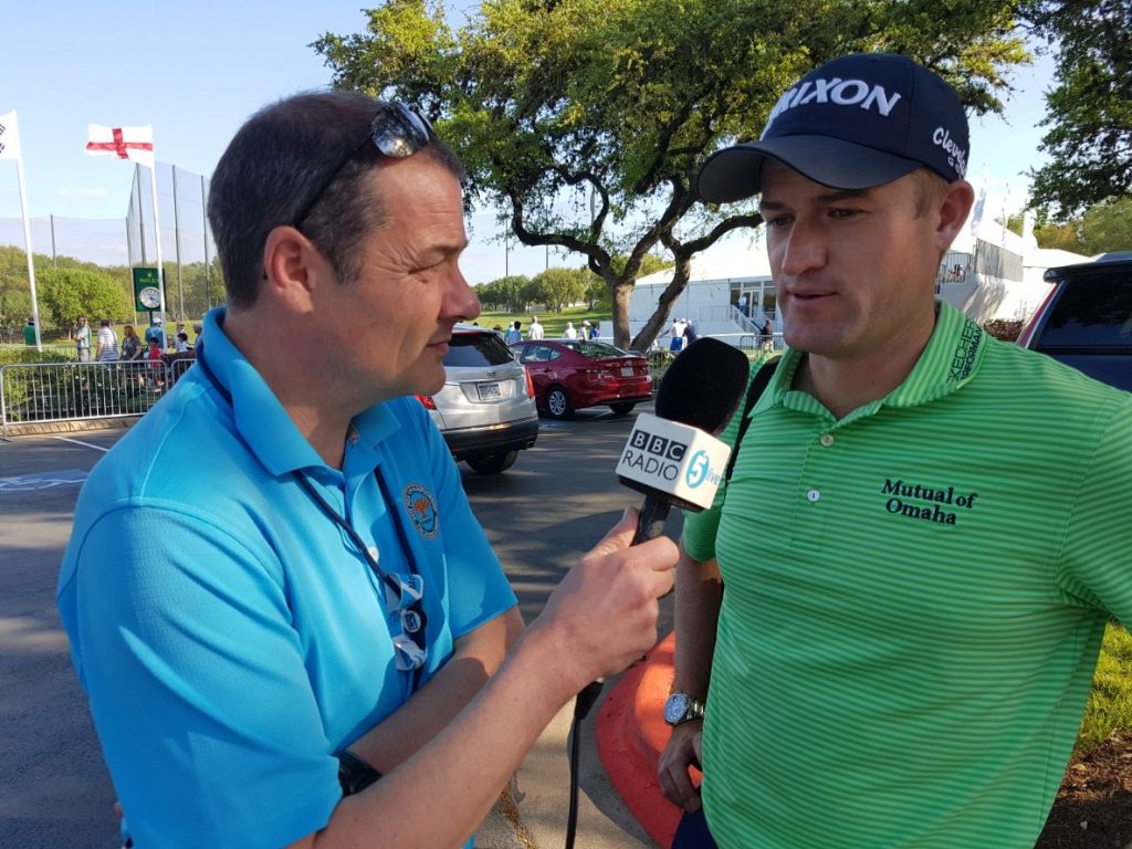 Russell Knox chatting with BBC 5 Live Iain Carter as the England flag flutters in the background at the Austin Country Club.